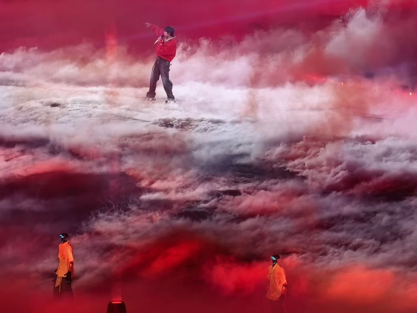 Humanoid robots in orange costumes performing in stage fog under red light